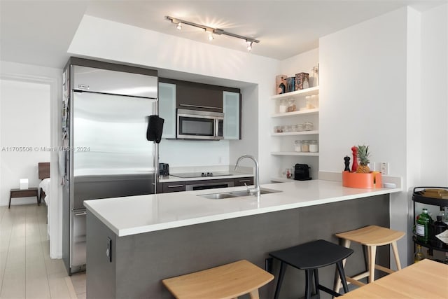 kitchen with sink, kitchen peninsula, stainless steel appliances, and a breakfast bar area