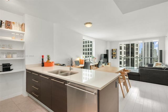 kitchen with kitchen peninsula, sink, stainless steel dishwasher, light hardwood / wood-style floors, and dark brown cabinetry