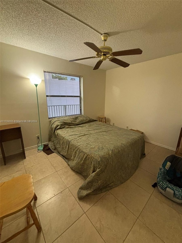 bedroom with ceiling fan, light tile patterned floors, and a textured ceiling