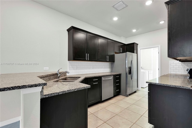 kitchen featuring sink, stainless steel appliances, backsplash, kitchen peninsula, and washer and dryer