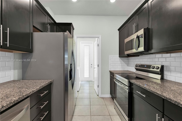 kitchen with light tile patterned flooring, dark stone countertops, appliances with stainless steel finishes, and tasteful backsplash