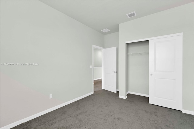 unfurnished bedroom with dark colored carpet and a closet