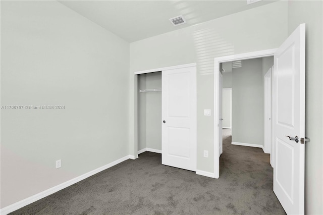 unfurnished bedroom with dark colored carpet and a closet