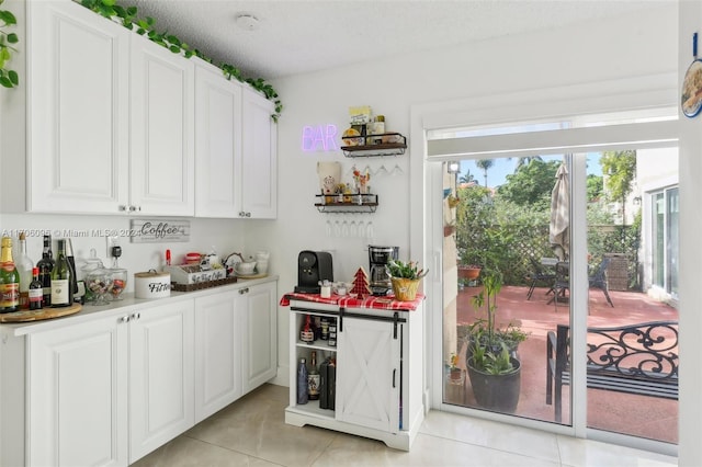 kitchen with white cabinets, light tile patterned flooring, and a textured ceiling