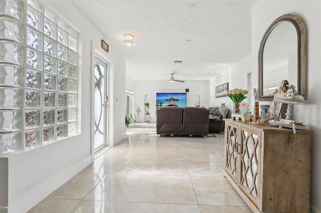 foyer featuring ceiling fan, light tile patterned floors, and a textured ceiling