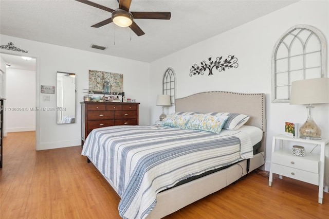 bedroom featuring ceiling fan, wood-type flooring, and a textured ceiling