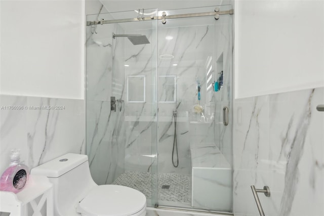 bathroom with a shower with door, tile walls, and toilet