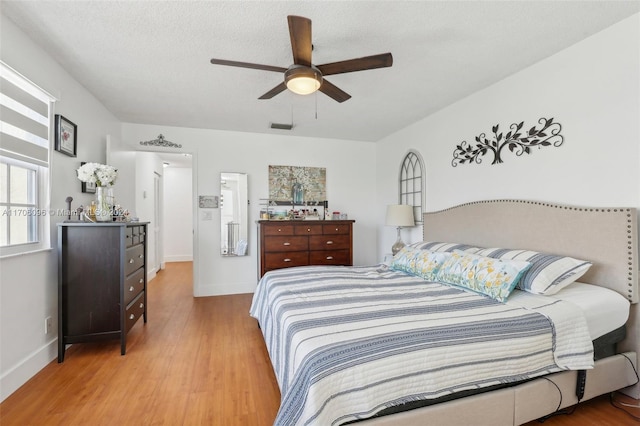 bedroom featuring ceiling fan, a textured ceiling, and light hardwood / wood-style flooring