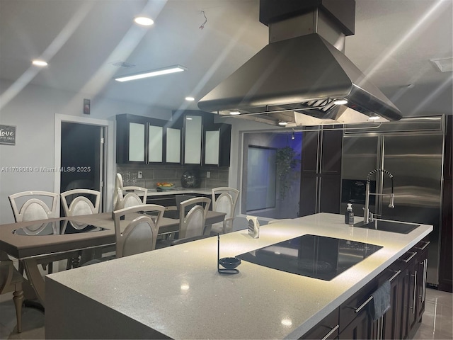 kitchen with tasteful backsplash, built in refrigerator, island range hood, black electric stovetop, and a kitchen island