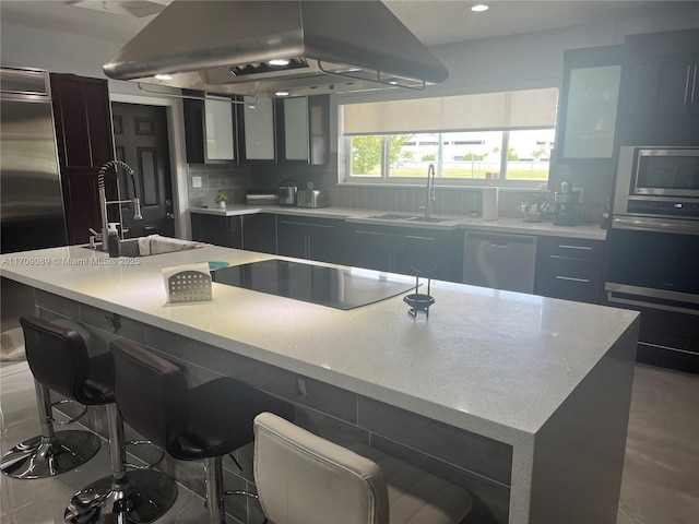 kitchen featuring island range hood, sink, stainless steel appliances, and an island with sink