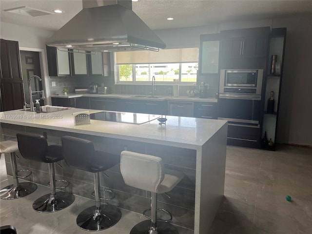 kitchen with a center island, stainless steel microwave, electric cooktop, sink, and island range hood