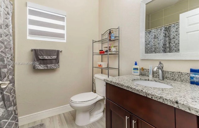 bathroom with a shower with shower curtain, hardwood / wood-style floors, vanity, and toilet