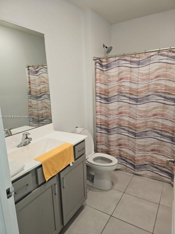 bathroom with toilet, vanity, tile patterned floors, and curtained shower