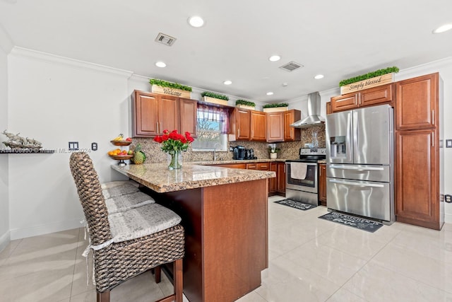 kitchen with wall chimney exhaust hood, decorative backsplash, appliances with stainless steel finishes, kitchen peninsula, and a breakfast bar area