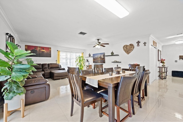 tiled dining area with ceiling fan and ornamental molding