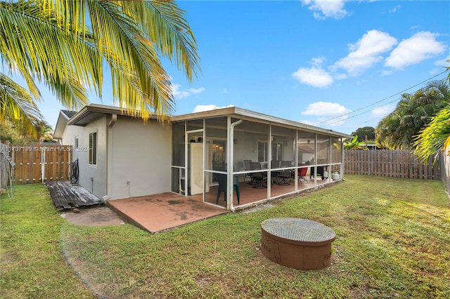 back of property featuring a lawn, a sunroom, and a patio