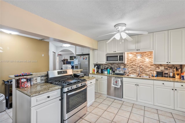 kitchen with light stone counters, sink, white cabinetry, and stainless steel appliances