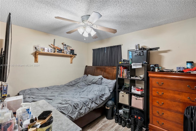 bedroom featuring ceiling fan, light hardwood / wood-style floors, and a textured ceiling