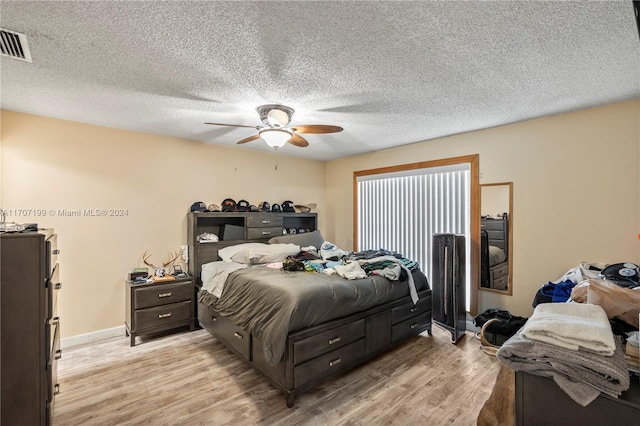 bedroom featuring ceiling fan, light hardwood / wood-style floors, and a textured ceiling