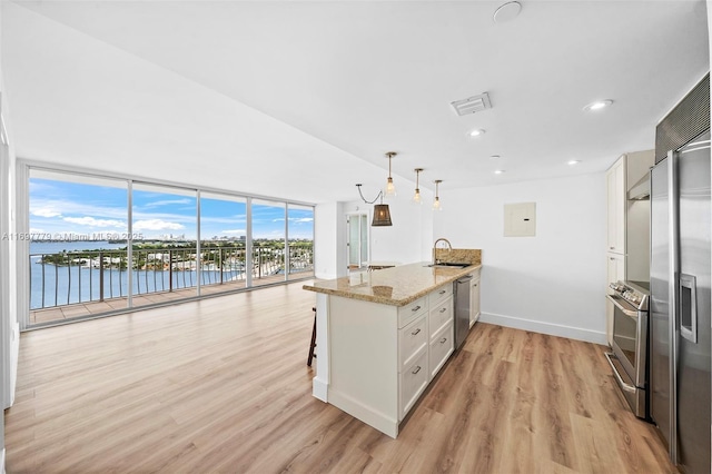 kitchen featuring decorative light fixtures, a water view, white cabinetry, light stone countertops, and a peninsula