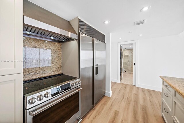 kitchen with sink, wall chimney exhaust hood, stainless steel appliances, light hardwood / wood-style flooring, and pendant lighting