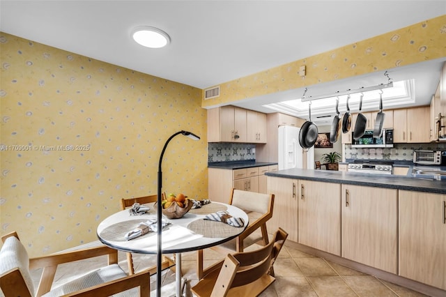 kitchen with light tile patterned floors, light brown cabinetry, and tasteful backsplash