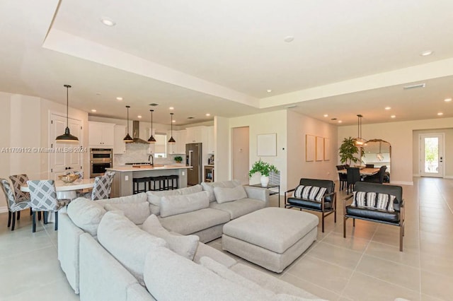 tiled living room with sink and a tray ceiling