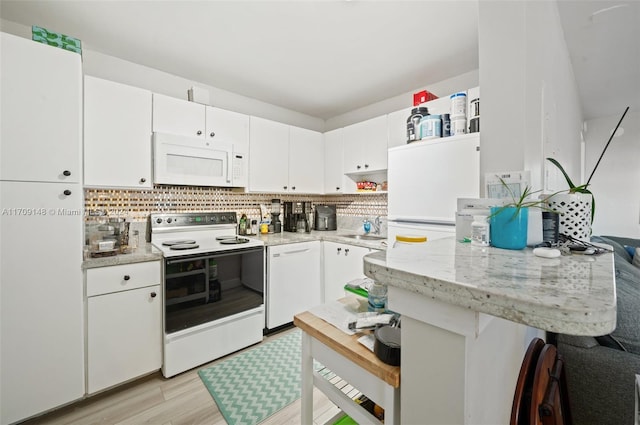 kitchen featuring white appliances, backsplash, white cabinets, sink, and light hardwood / wood-style flooring