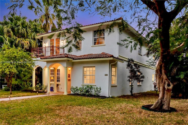 view of front of home with a lawn and a balcony