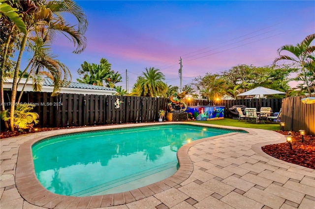 pool at dusk featuring a patio