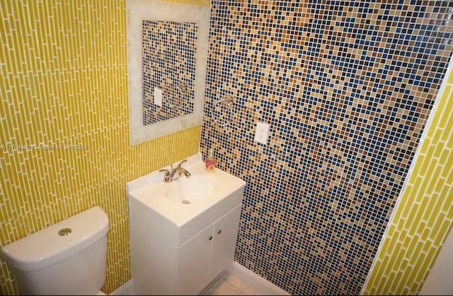 bathroom with vanity, toilet, and tile walls