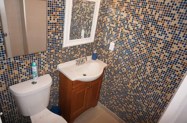 bathroom featuring tile patterned floors, vanity, toilet, and tile walls