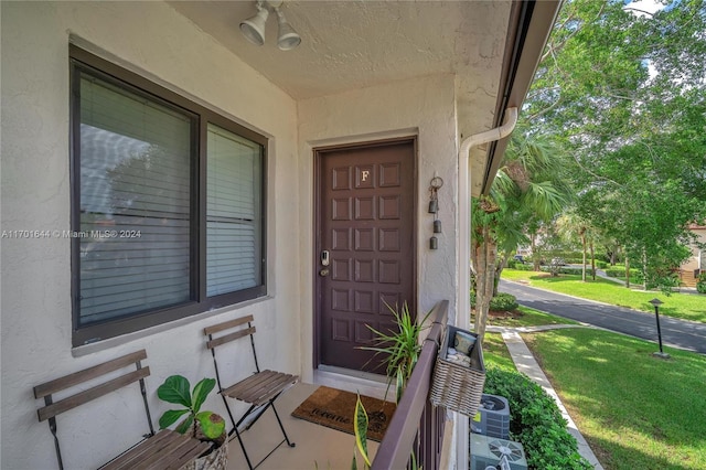 doorway to property featuring cooling unit and a yard