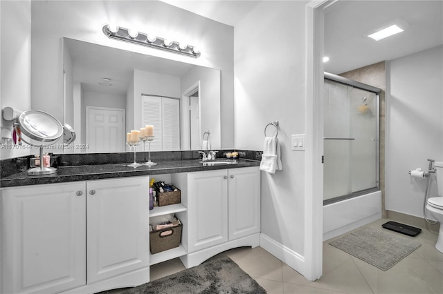 full bathroom with tile patterned floors, vanity, bath / shower combo with glass door, and toilet