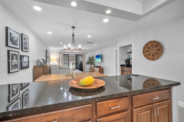 kitchen featuring an inviting chandelier, hanging light fixtures, and dark stone countertops