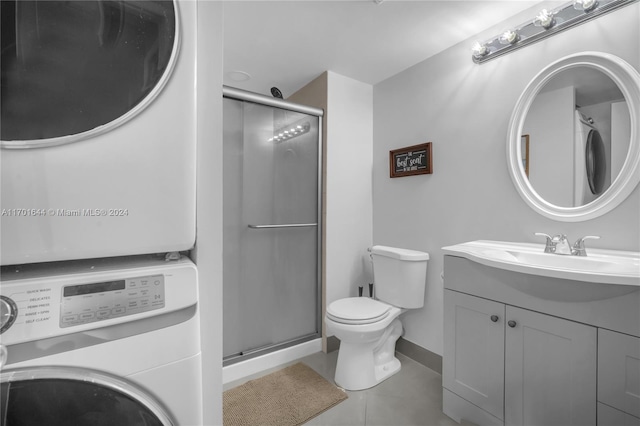 bathroom with an enclosed shower, vanity, tile patterned floors, and stacked washer / dryer