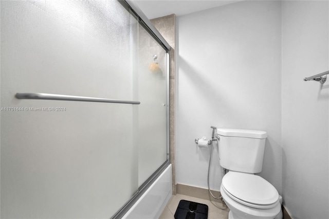 bathroom featuring tile patterned floors, toilet, and enclosed tub / shower combo