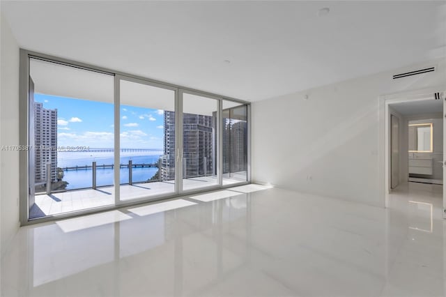 tiled empty room with a water view and floor to ceiling windows