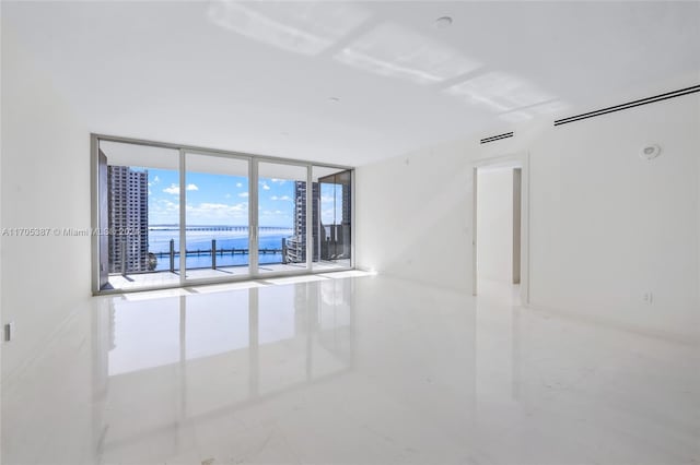 spare room featuring expansive windows and a water view