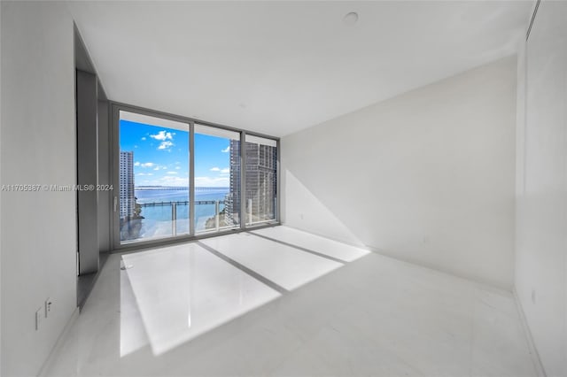 spare room featuring a water view and a wall of windows