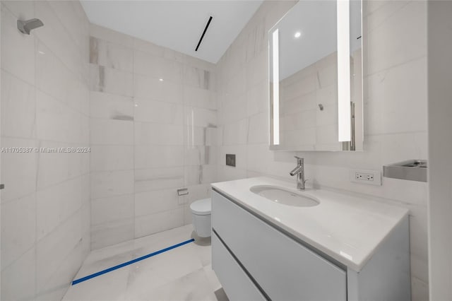 bathroom with vanity, toilet, and tile walls