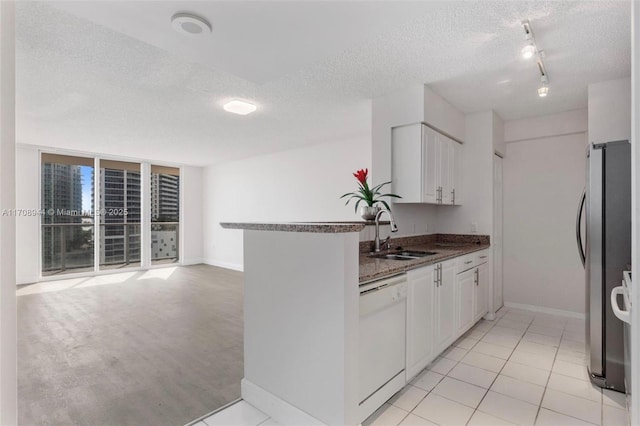 kitchen with white cabinetry, dishwasher, sink, stainless steel fridge, and kitchen peninsula