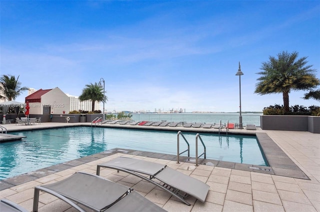 view of pool with a patio area and a water view