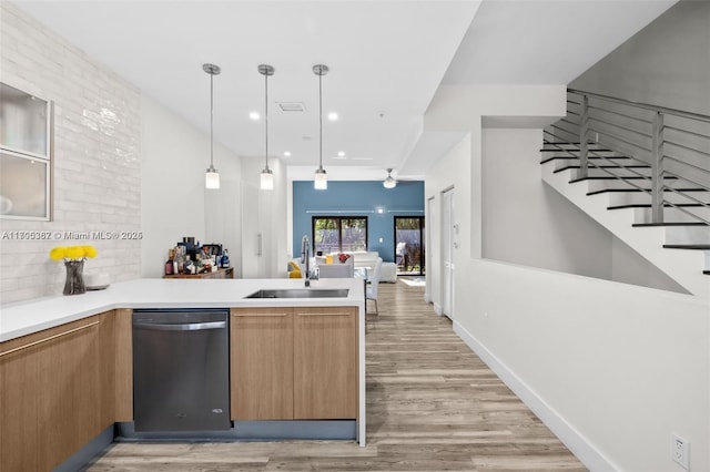 kitchen featuring decorative light fixtures, kitchen peninsula, dishwasher, and sink