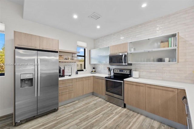 kitchen featuring light hardwood / wood-style floors, backsplash, stainless steel appliances, and light brown cabinetry