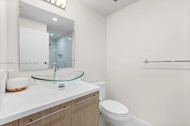 bathroom featuring toilet, vanity, and a shower with door