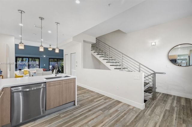 kitchen featuring stainless steel dishwasher, decorative light fixtures, sink, and hardwood / wood-style flooring