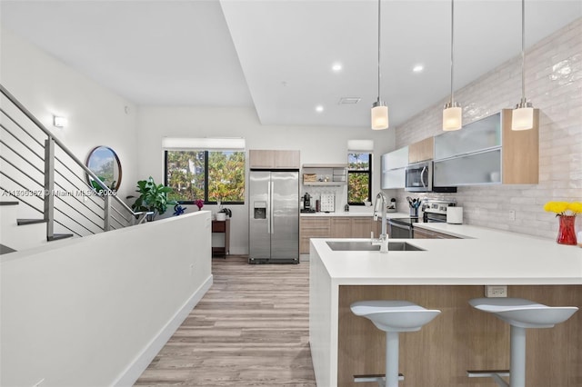 kitchen featuring stainless steel appliances, tasteful backsplash, pendant lighting, a breakfast bar, and sink