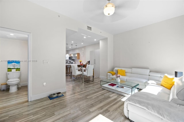 living room with ceiling fan and light hardwood / wood-style flooring