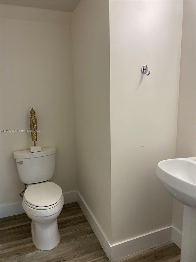 bathroom featuring toilet and wood-type flooring